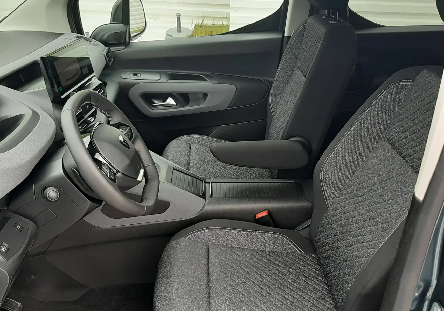 Vue intérieure côté conducteur du Peugeot Rifter 2026 bleu Kiama, avec sièges tissu gris et tableau de bord moderne.