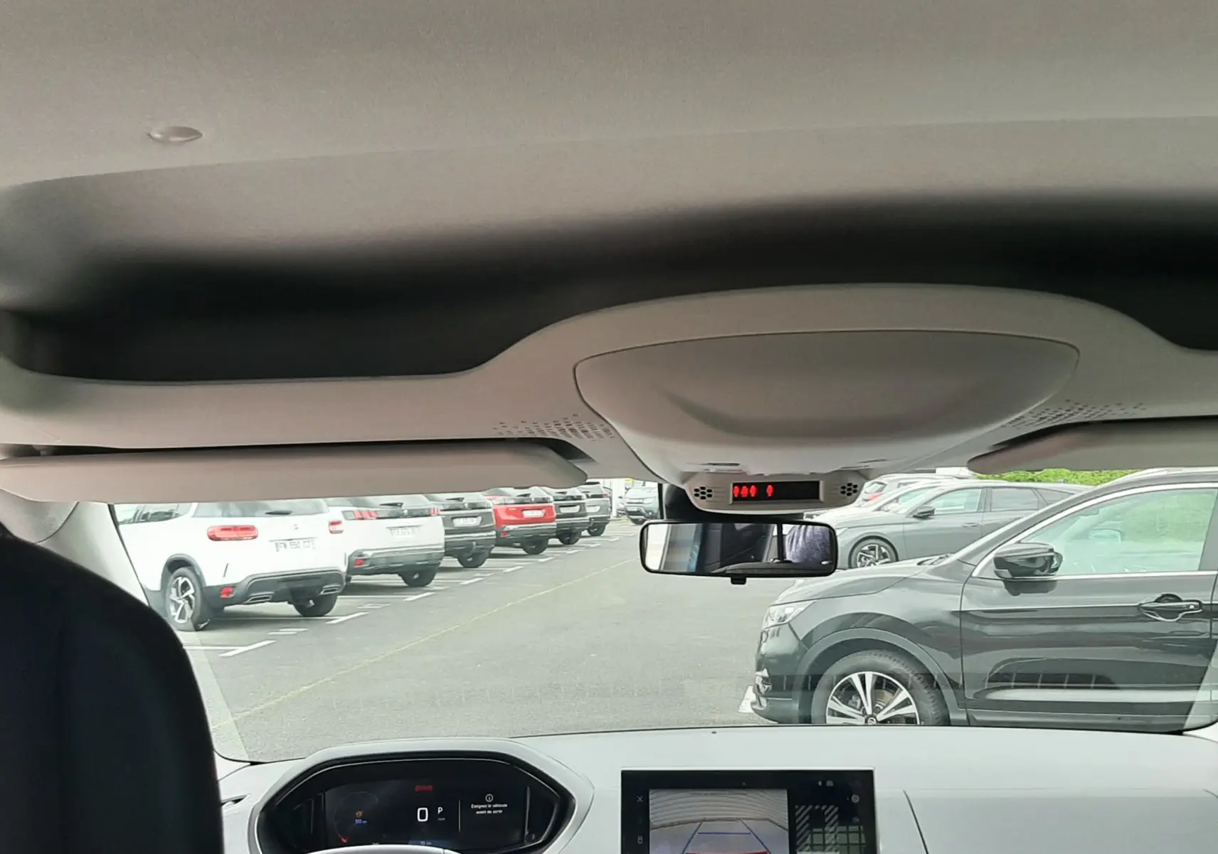 Vue intérieure avant du Peugeot Rifter bleu Kiama 2026, avec tableau de bord numérique et écran de caméra de recul.