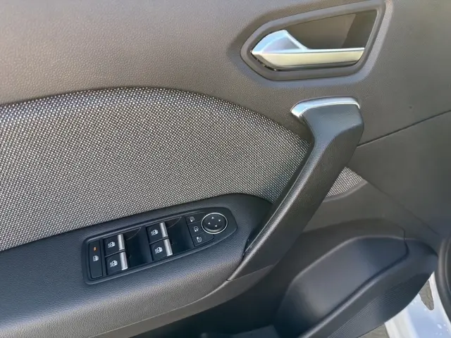 Détail de la porte intérieure côté conducteur de la Renault Symbioz gris clair, avec commandes des vitres et poignée noire.