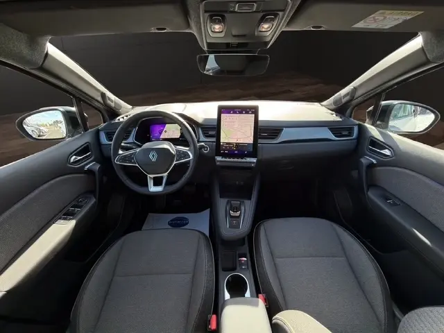Vue intérieure frontale du tableau de bord et des sièges gris du Renault Symbioz techno E-Tech 2025 avec écran tactile central vertical.