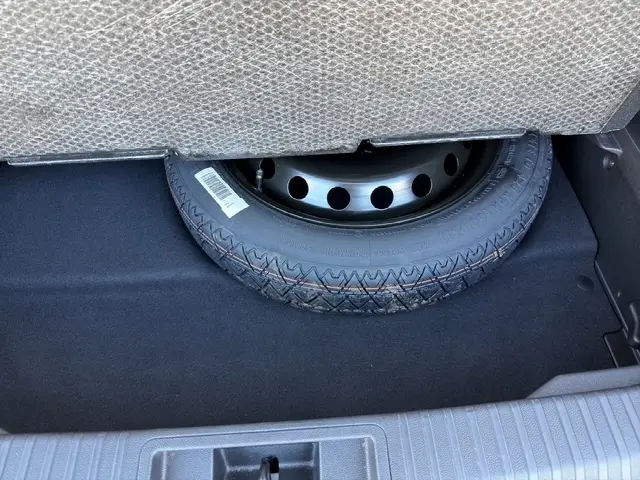 Pneu de secours sous la banquette arrière grise du coffre d’un Renault Symbioz gris clair 2025.