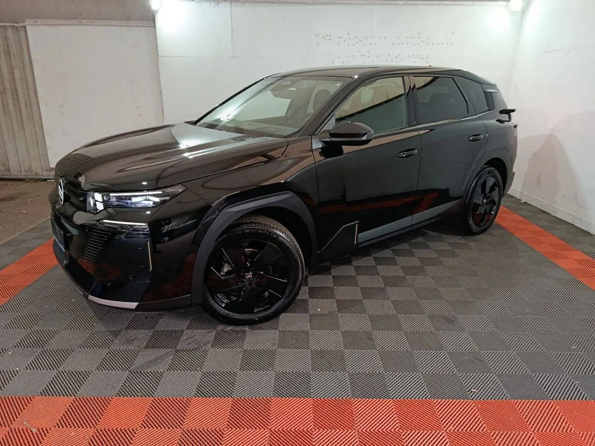 Vue 3/4 avant droite d'un Citroën C5 hybride noir avec jantes noires et lignes anguleuses modernes.
