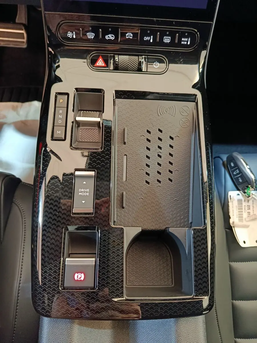 Vue plongeante sur la console centrale noire brillante du Citroën C5 Hybride 145ch avec commandes et porte-gobelet.
