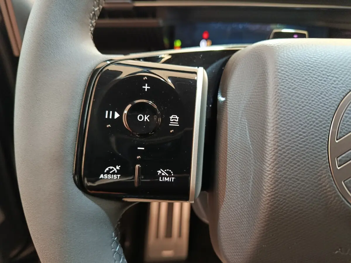 Gros plan sur la commande multifonctions gauche du volant cuir noir du Citroën C5 Hybride 2026.