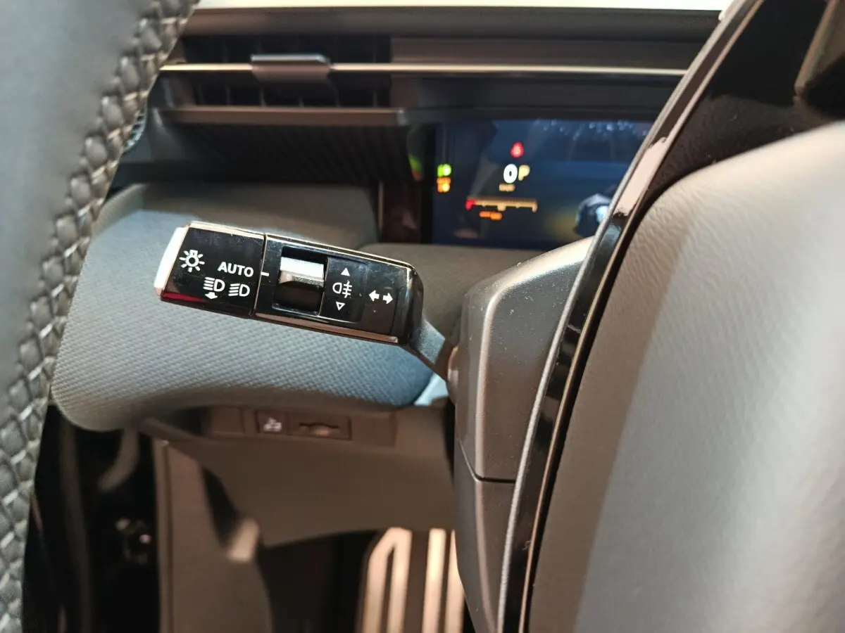 Gros plan sur la commande des feux et clignotants à gauche du volant dans l’habitacle noir du Citroën C5 Hybride.