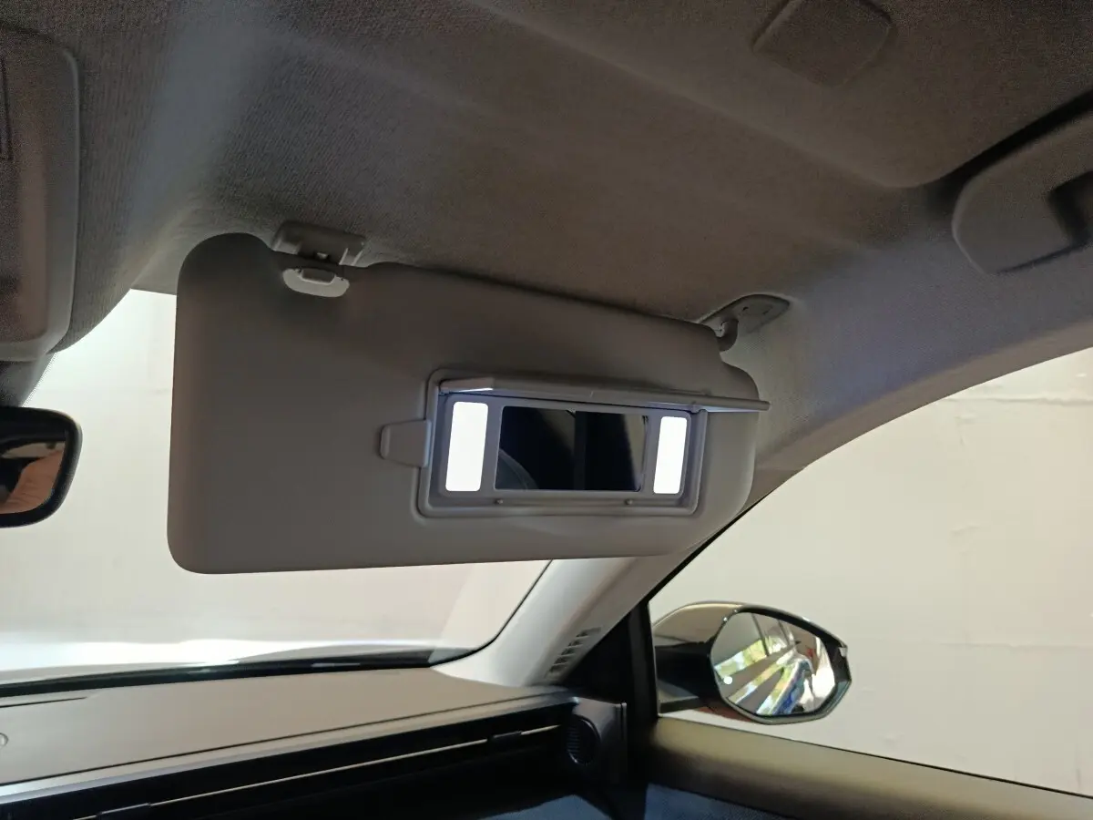 Intérieur de la Citroën C5 Hybride noir, vue côté passager avec pare-soleil et miroir éclairé déployé.