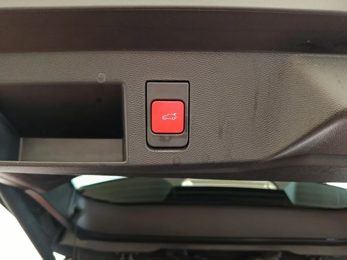 Bouton rouge d'ouverture électrique du coffre sur le hayon intérieur d'une Citroën C5 Hybride noire 2026.