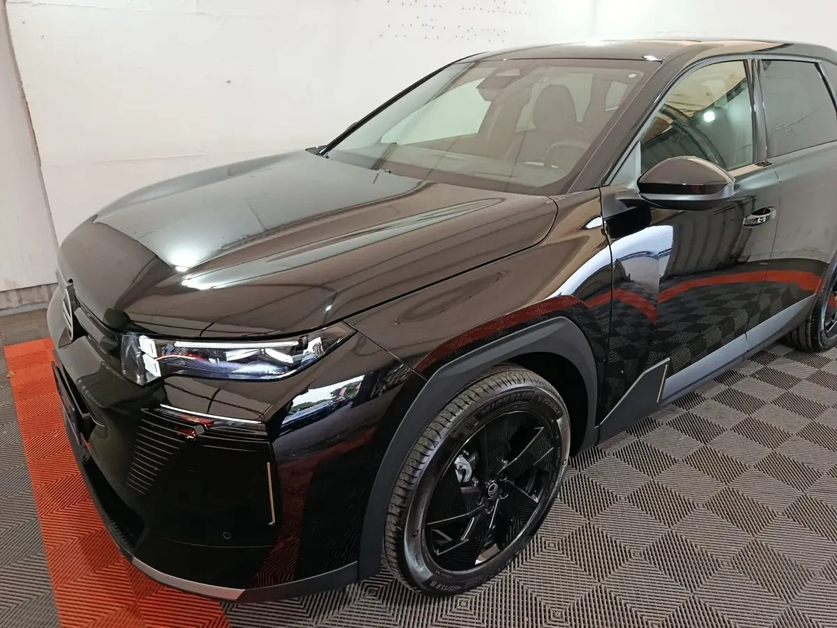 Vue 3/4 avant droit d'une Citroën C5 hybride noire avec phares LED et jantes noires distinctives.