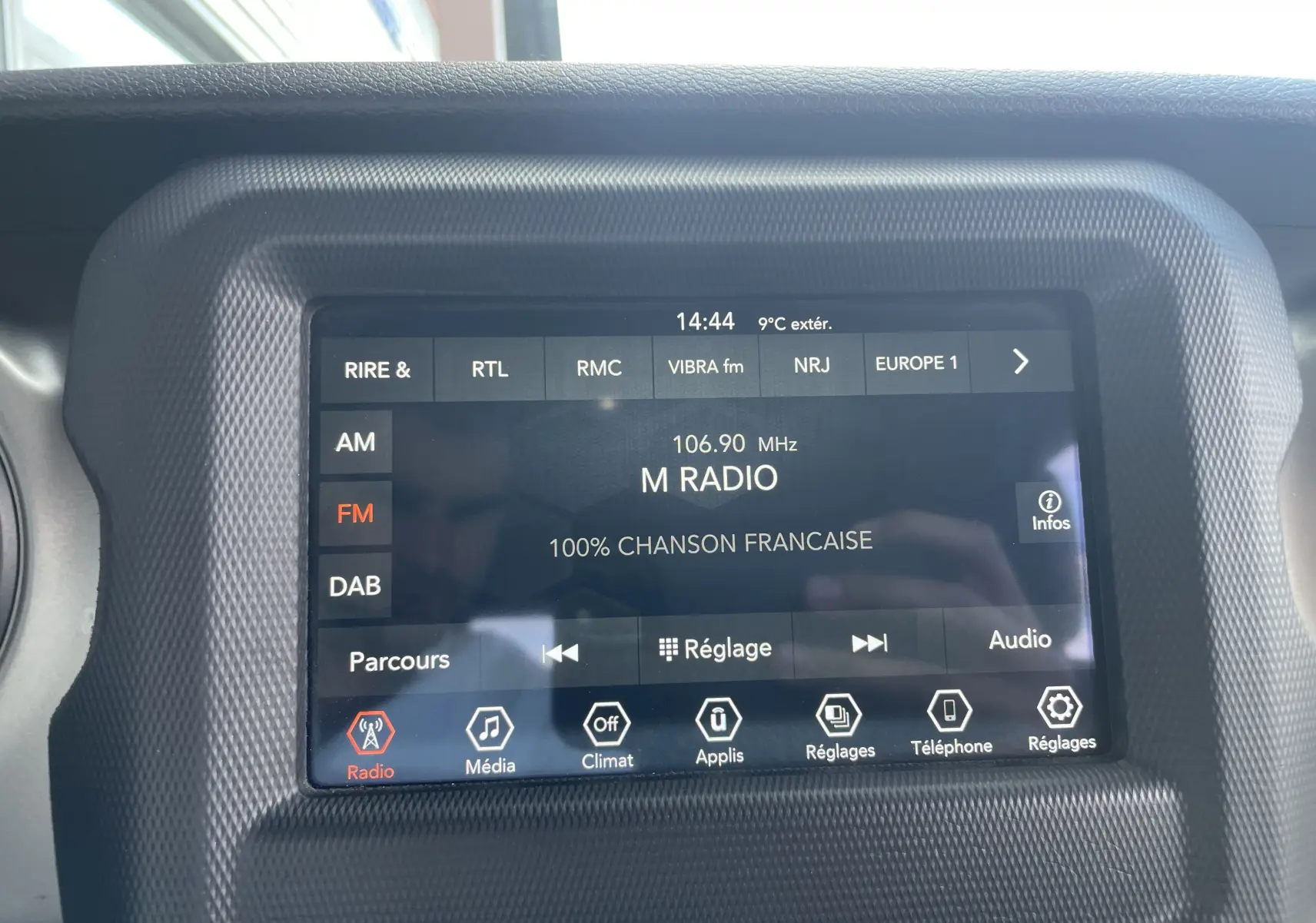 Écran tactile central de la Jeep Wrangler 2018 affichant la radio FM sur 106.90 MHz avec interface noire texturée.