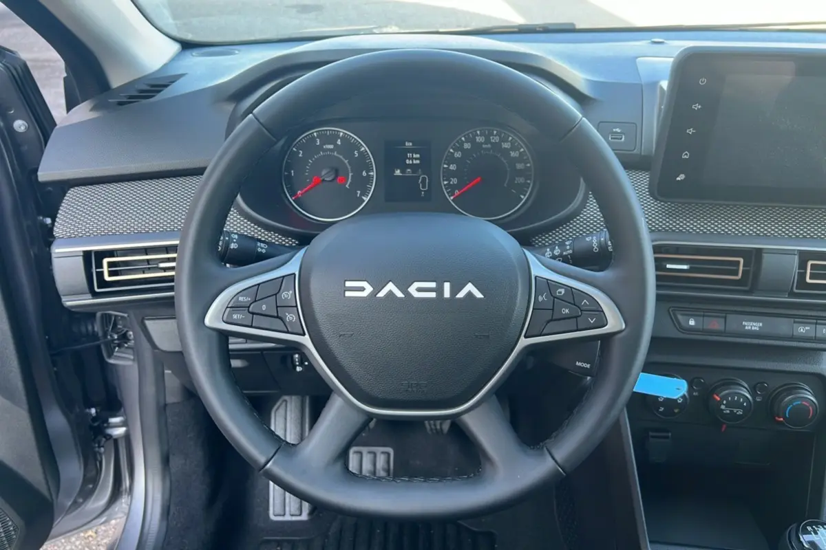 Vue intérieure centrée sur le volant DACIA d'une Sandero Stepway 2025, avec tableau de bord et commandes visibles.