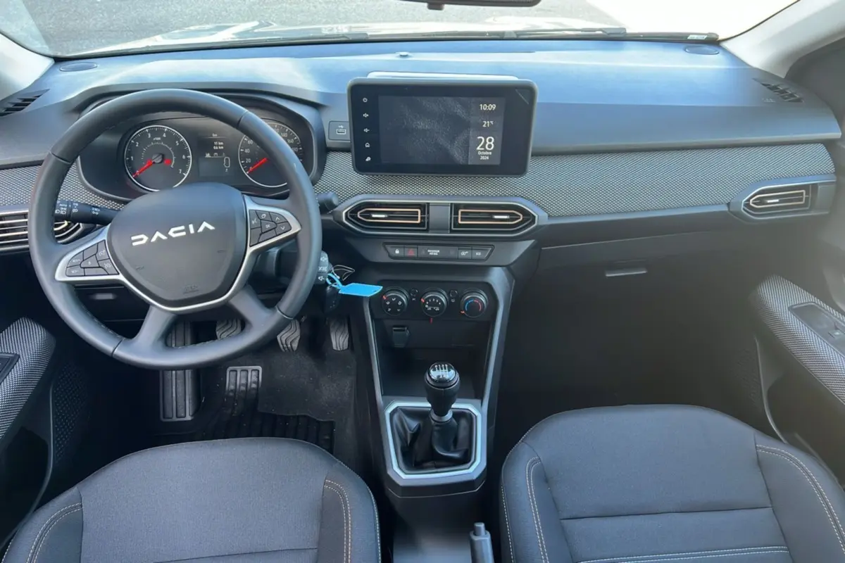 Intérieur de la Dacia Sandero Stepway 2025, vue du tableau de bord avec volant, écran tactile et levier de vitesses manuel.