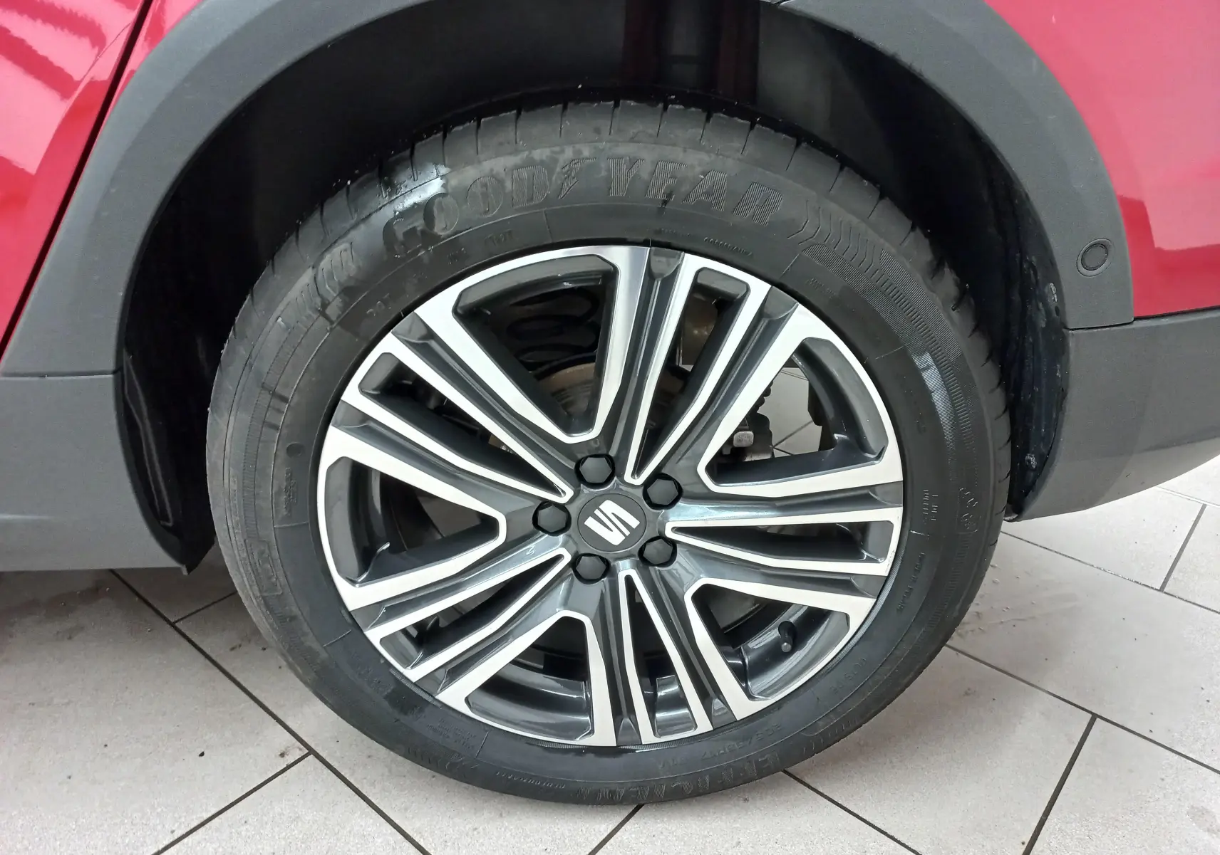 Gros plan sur la roue avant droite du SEAT Arona rouge Désir avec jante alliage bicolore et pneu Goodyear.