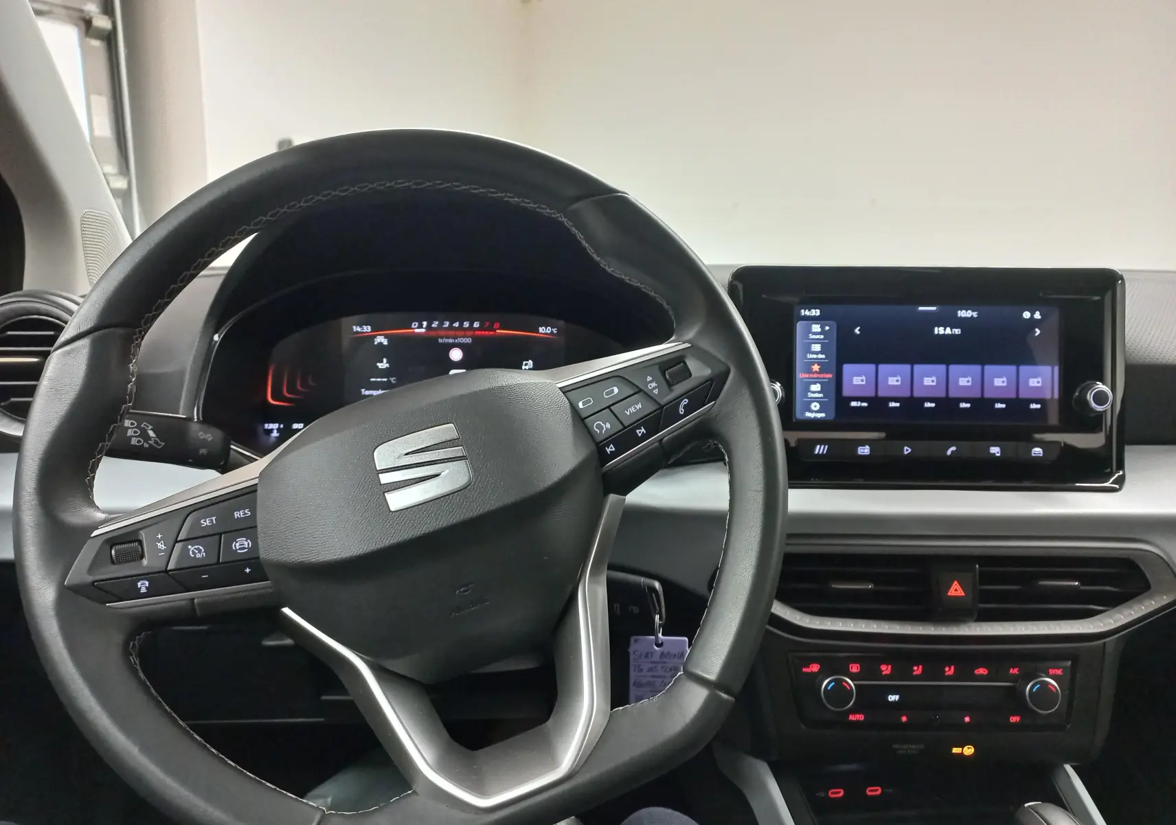 Vue intérieure centrée sur le volant et l’écran tactile du tableau de bord d’une SEAT Arona 2025.