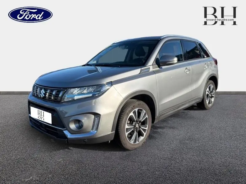 Suzuki Vitara 1.4 Boosterjet Hybrid gris Galactic, vue 3/4 avant avec jantes alu et calandre chromée.