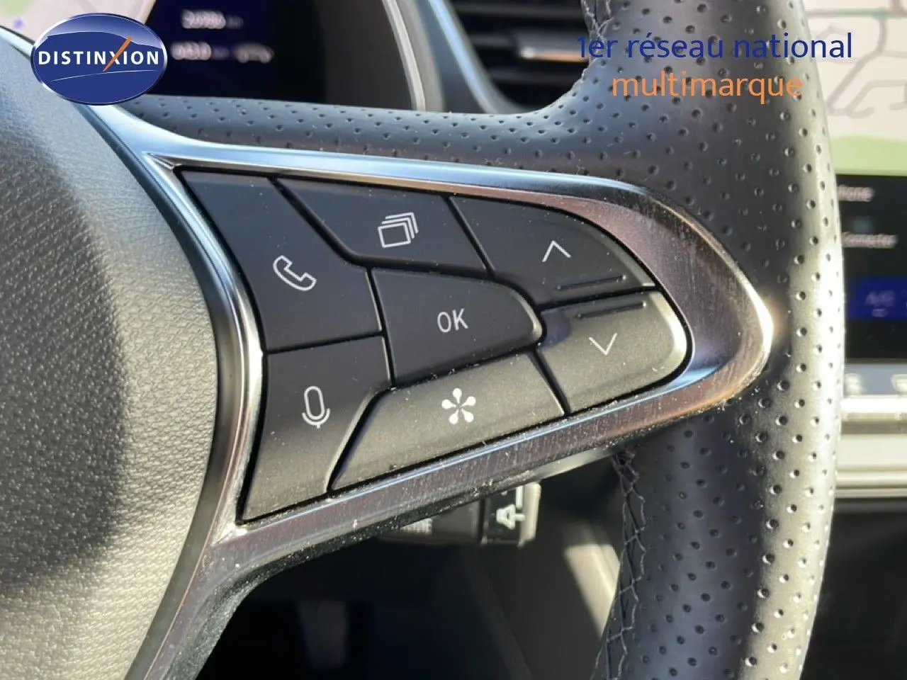 Gros plan sur les commandes multifonctions en plastique noir et chrome du volant perforé côté gauche du Renault Symbioz gris cassiopée.