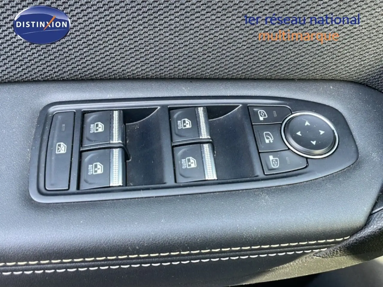 Vue rapprochée des commandes des vitres et rétroviseurs sur la porte côté gauche d’un Renault Symbioz gris cassiopée métal.
