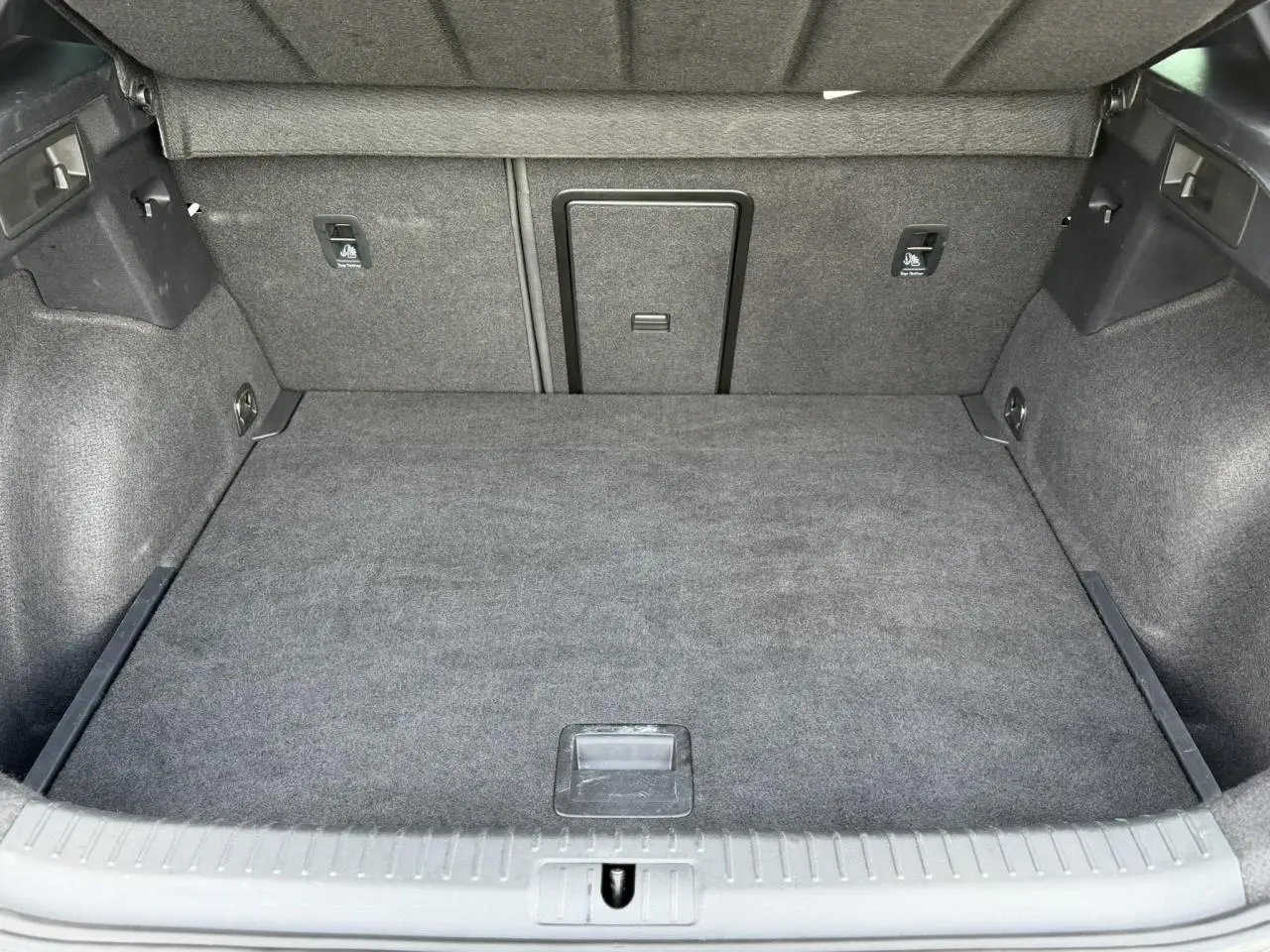Coffre ouvert du CUPRA Formentor blanc Neige, vue intérieure montrant un espace de chargement propre et bien fini en tissu gris.
