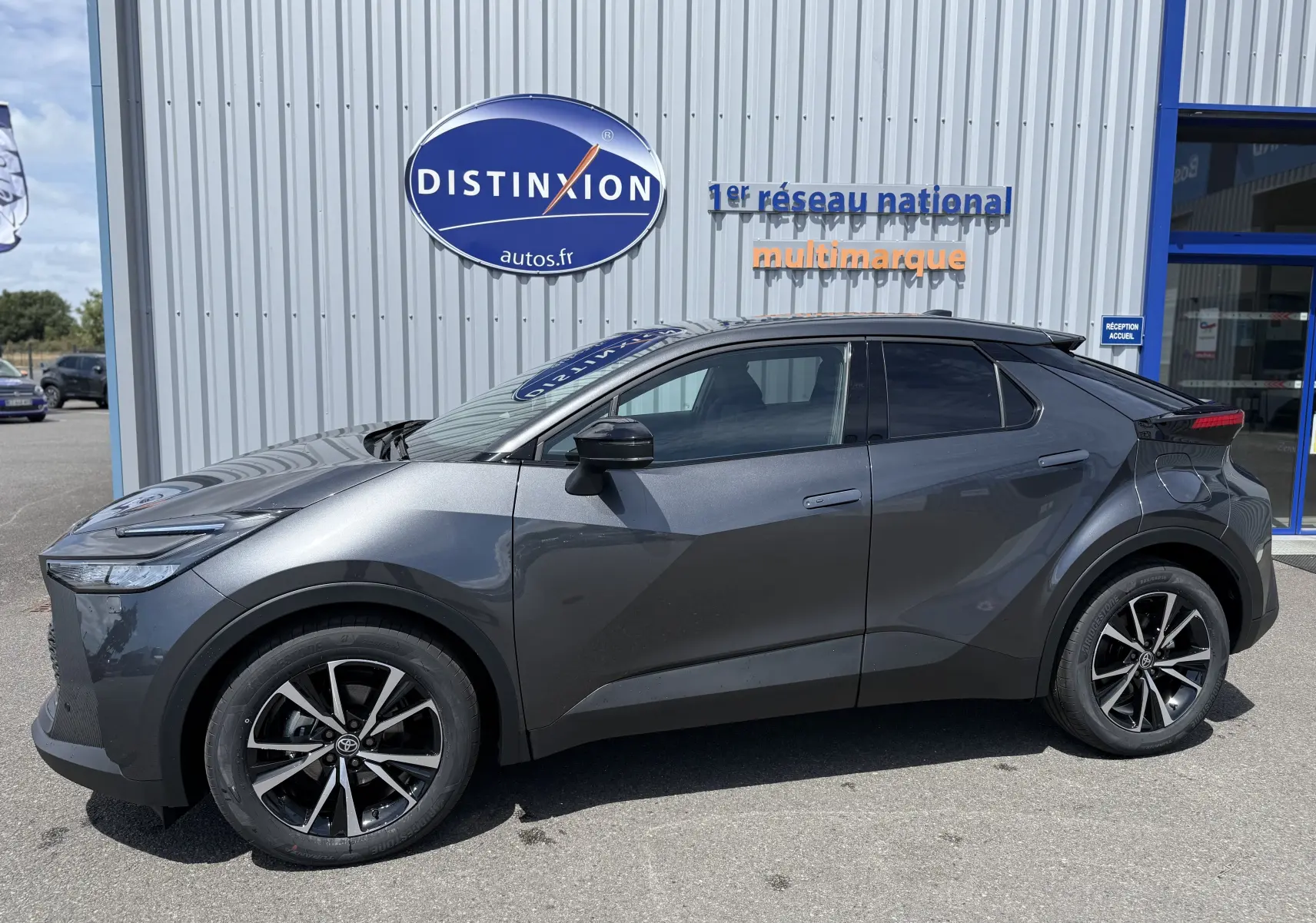 Profil côté gauche du Toyota C-HR 1.8 Hybride 140 Style gris atlas avec jantes alliage et lignes anguleuses marquées.