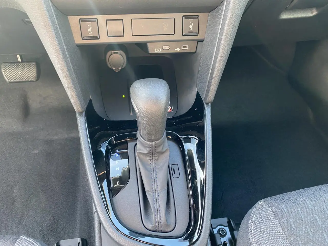 Le levier de vitesse automatique gris de la Toyota Yaris Cross 2025 vu de dessus avec ports USB-C et commandes chauffantes.