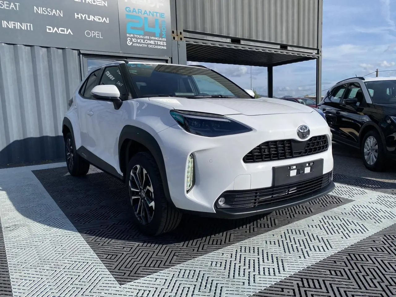 Toyota Yaris Cross blanc pur vue 3/4 avant droit avec jantes alliage et toit noir contrasté.