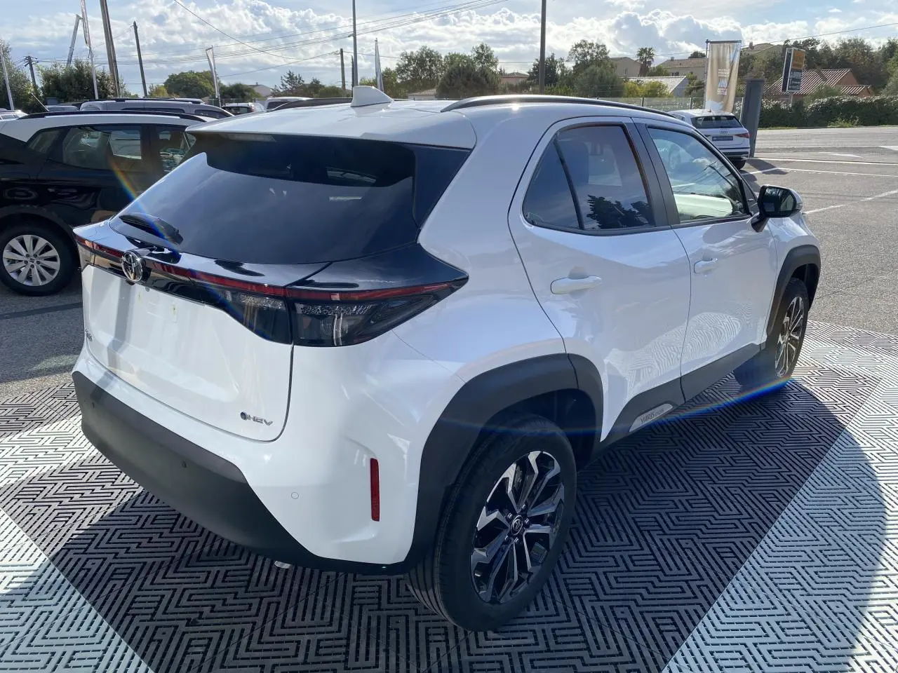 Toyota Yaris Cross blanc pur en 3/4 arrière droit, avec toit noir, jantes alliage 17'' et feux arrière LED séquentiels.