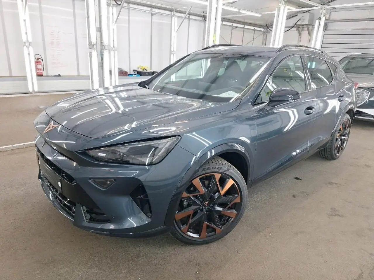 Vue 3/4 avant d'une CUPRA Formentor gris magnétique avec jantes alliage 19'' cuivrées dans un garage.