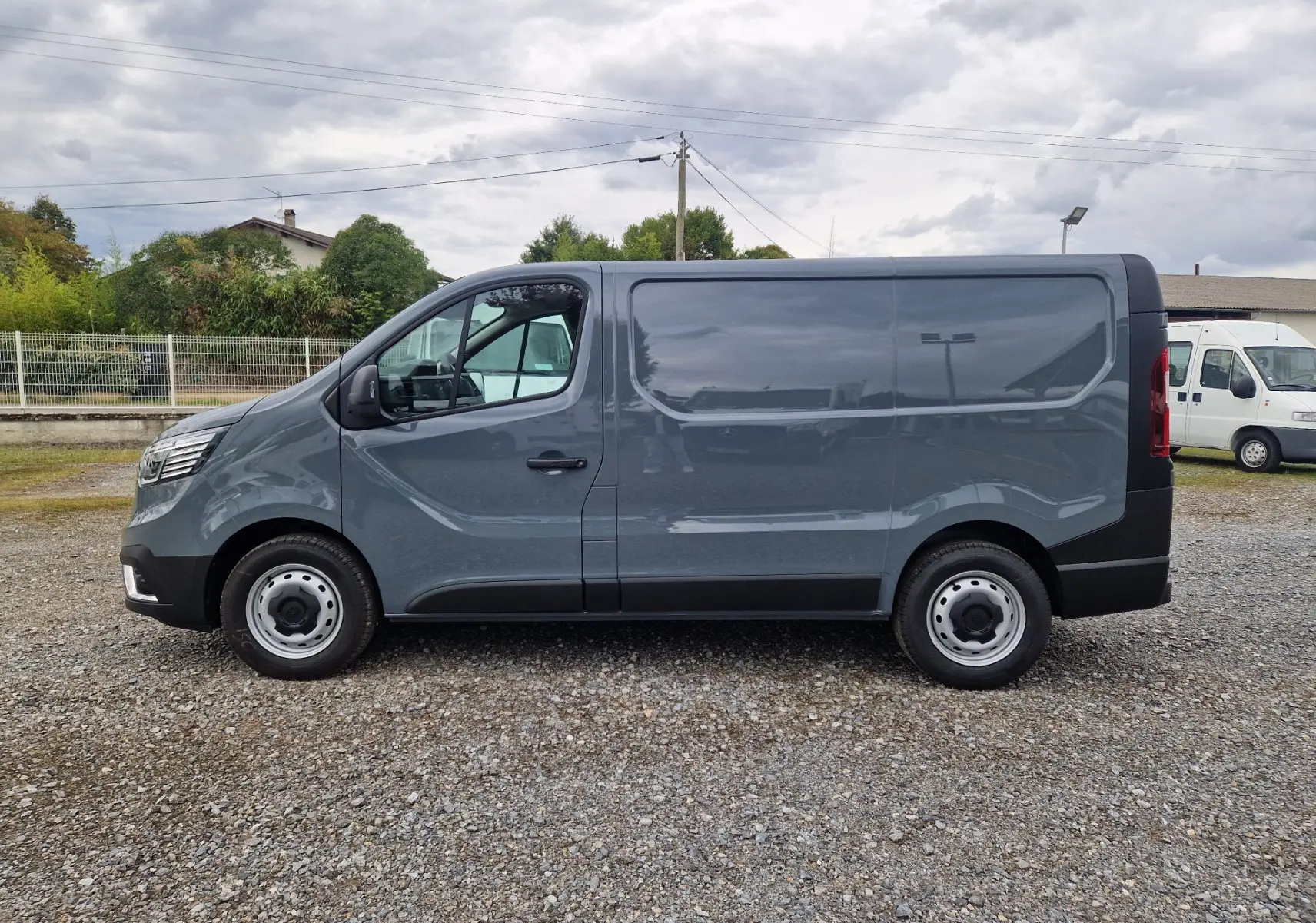 Profil côté gauche du Renault Trafic Fourgon gris urbain 2025, avec jantes acier et carrosserie lisse sans fenêtres latérales.