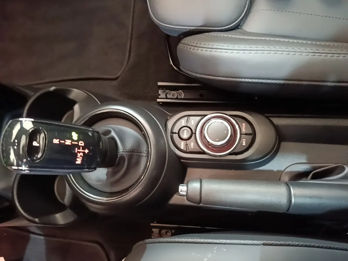 Vue rapprochée du levier de vitesses automatique et molette de commande centrale de la MINI Cooper noire, intérieur cuir gris.