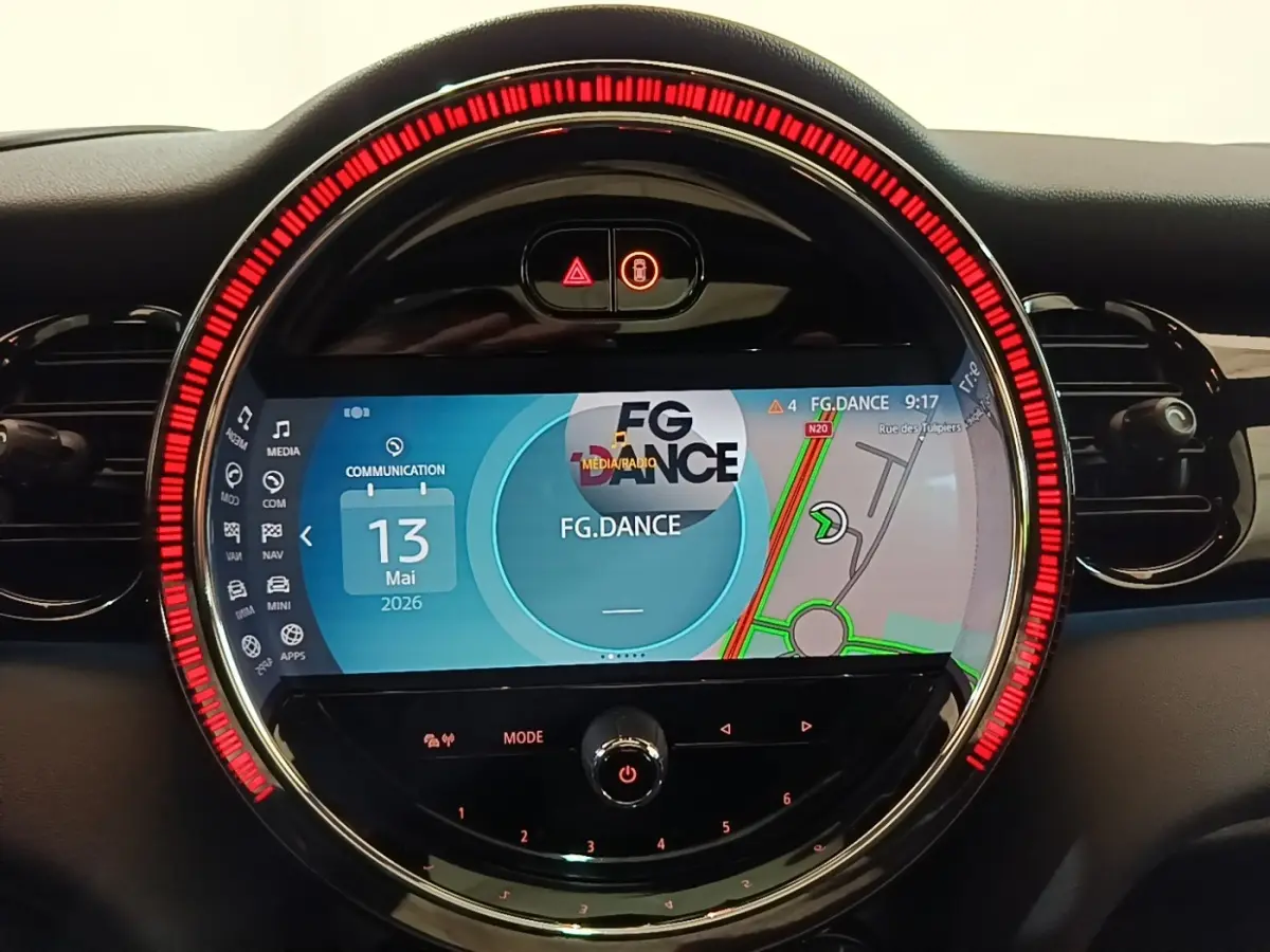 Gros plan sur l’écran tactile central rond du tableau de bord de la MINI noire, avec affichage de navigation et média.
