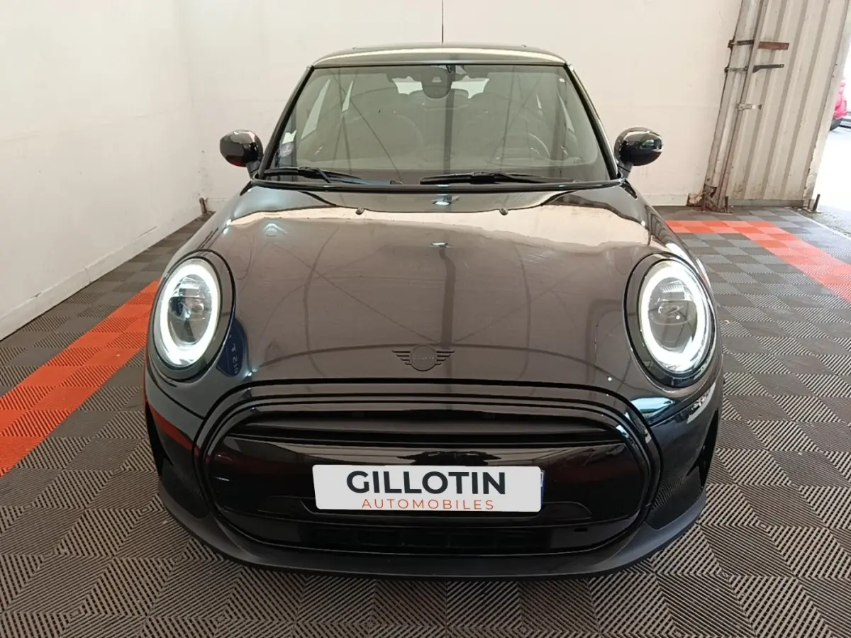 Vue frontale d'une MINI Cooper Edition Premium Plus noire avec phares LED circulaires allumés en intérieur.