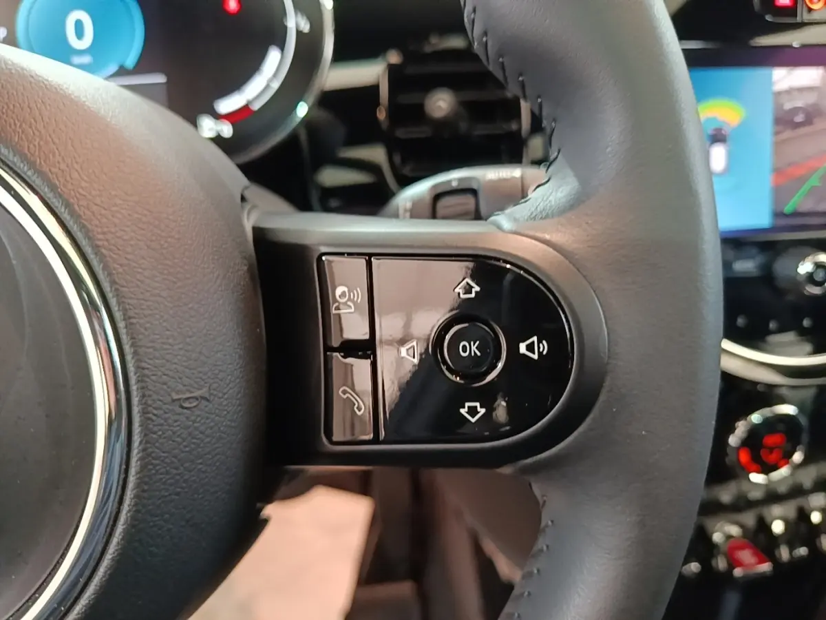 Gros plan sur la partie droite du volant cuir noir de la MINI Cooper 2023 avec commandes multifonctions et tableau de bord numérique.