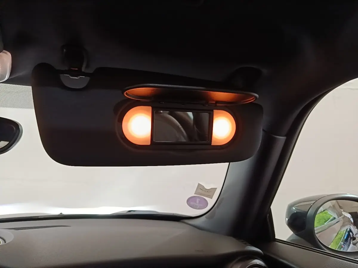 Détail intérieur du pare-soleil avec miroir éclairé dans une MINI Cooper Edition Premium Plus noire, vue côté conducteur.