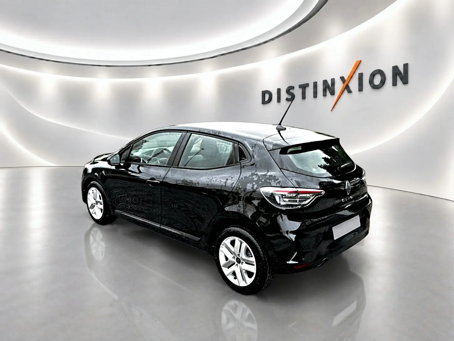 Vue 3/4 arrière droite d'une Renault Clio V noire avec feux LED et jantes argentées dans un showroom lumineux.