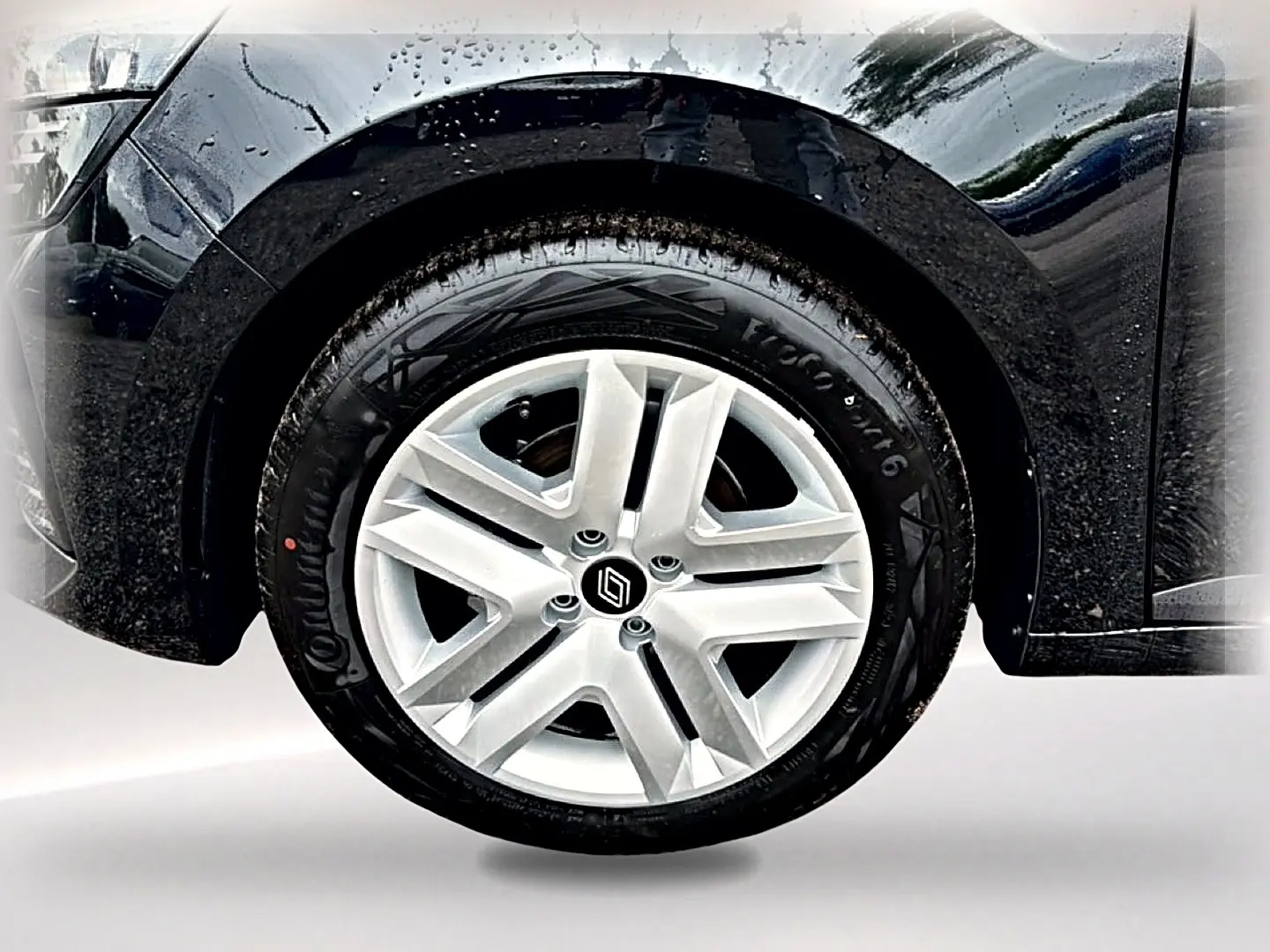Gros plan sur la roue avant droite de la Renault Clio V noire, mettant en valeur la jante en alliage argentée et le logo Renault.