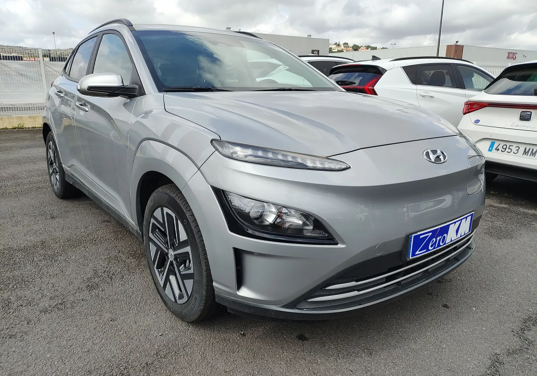 Vue 3/4 avant gauche d'un Hyundai Kona électrique gris métallisé avec jantes alliage et calandre lisse.