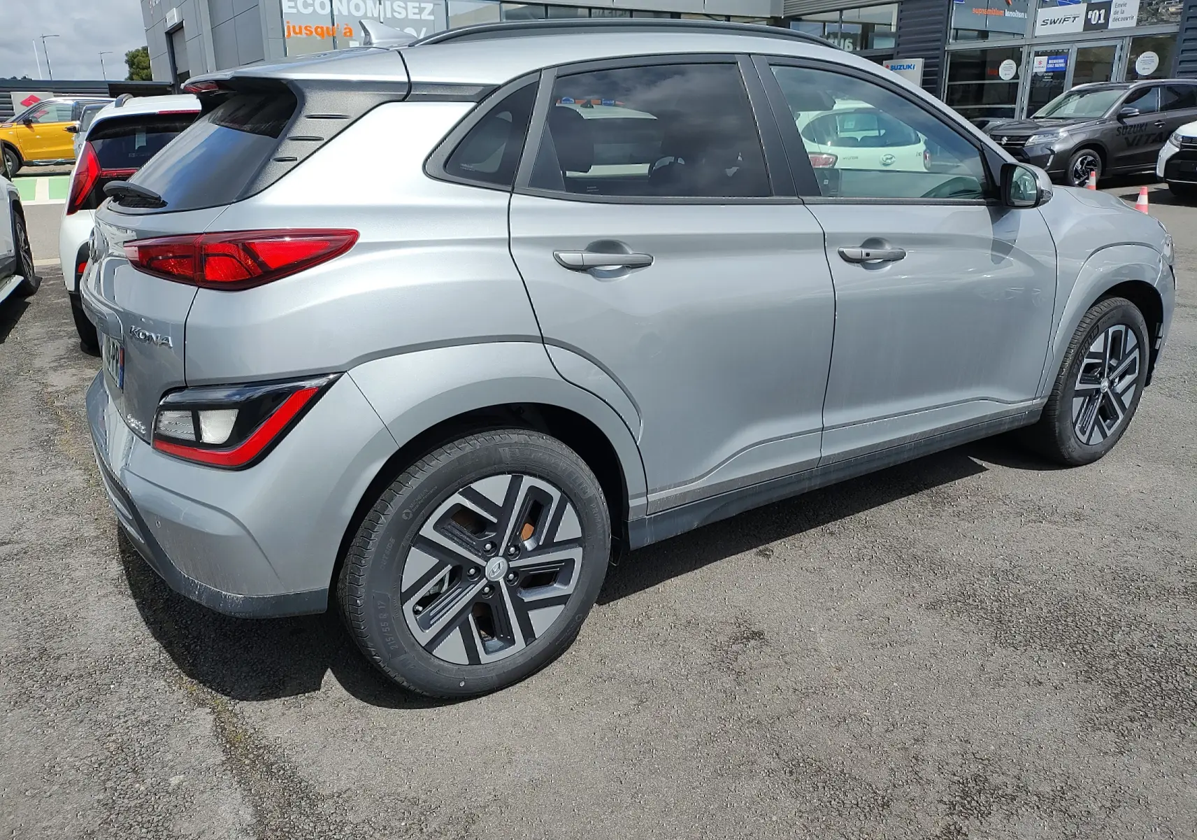 Vue 3/4 arrière droite d'un Hyundai Kona électrique gris métallisé avec jantes alliage et vitres surteintées.