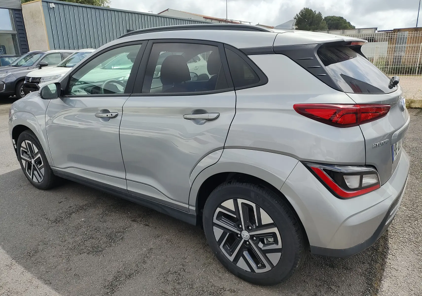 Vue 3/4 arrière côté gauche d'un Hyundai Kona électrique gris métallisé avec jantes alliage et vitres surteintées
