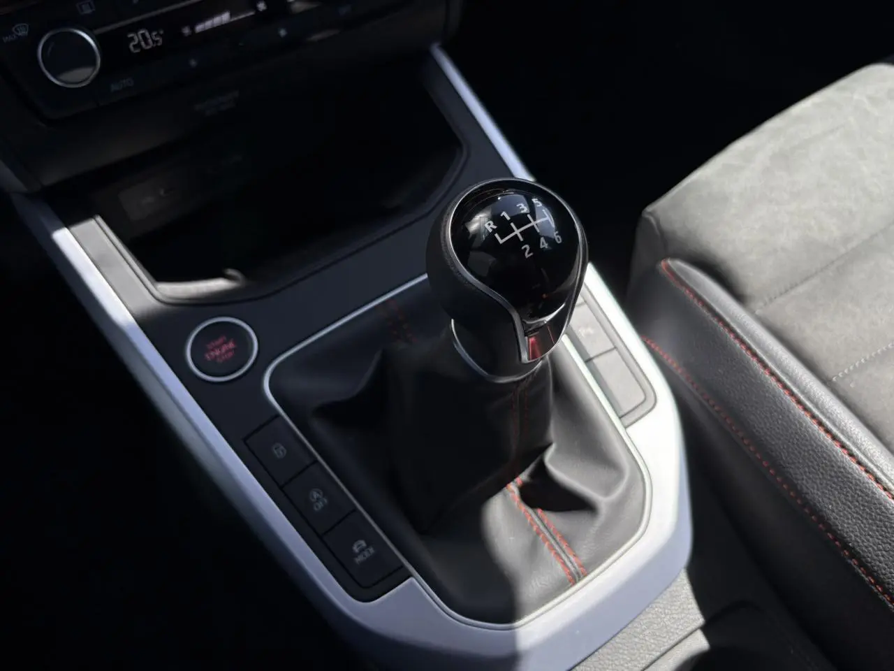 Gros plan sur le levier de vitesse manuel du SEAT Arona TSI 110 FR 2024 avec coutures rouges et bouton start/stop.