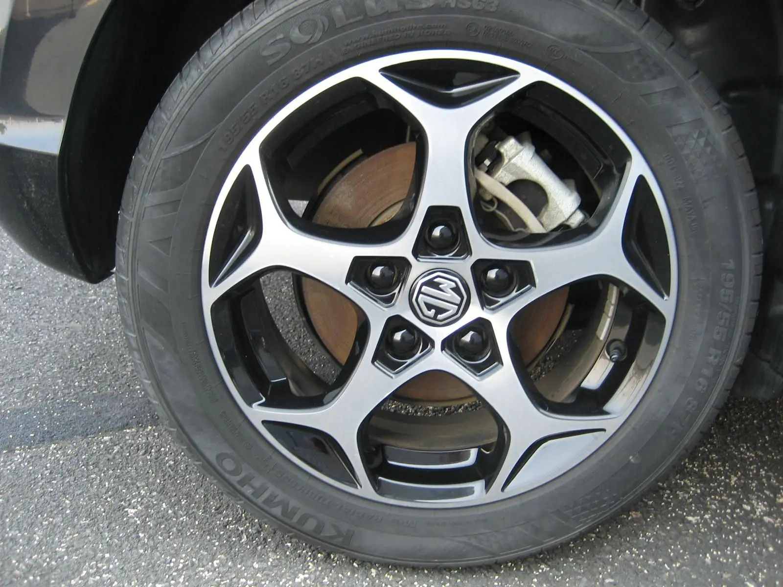 Gros plan sur la jante alliage noire et argentée du MG3 1.5 HYBRID+ 195 CH LUXURY noir, frein à disque visible.