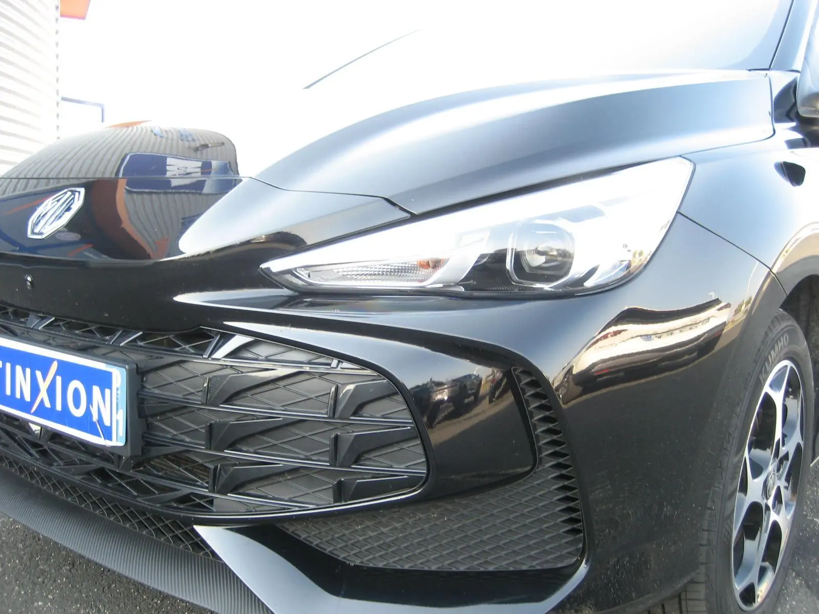 Gros plan sur l'avant droit noir brillant du MG3 1.5 HYBRID+ 195 CH LUXURY avec calandre et phare LED distinctifs.