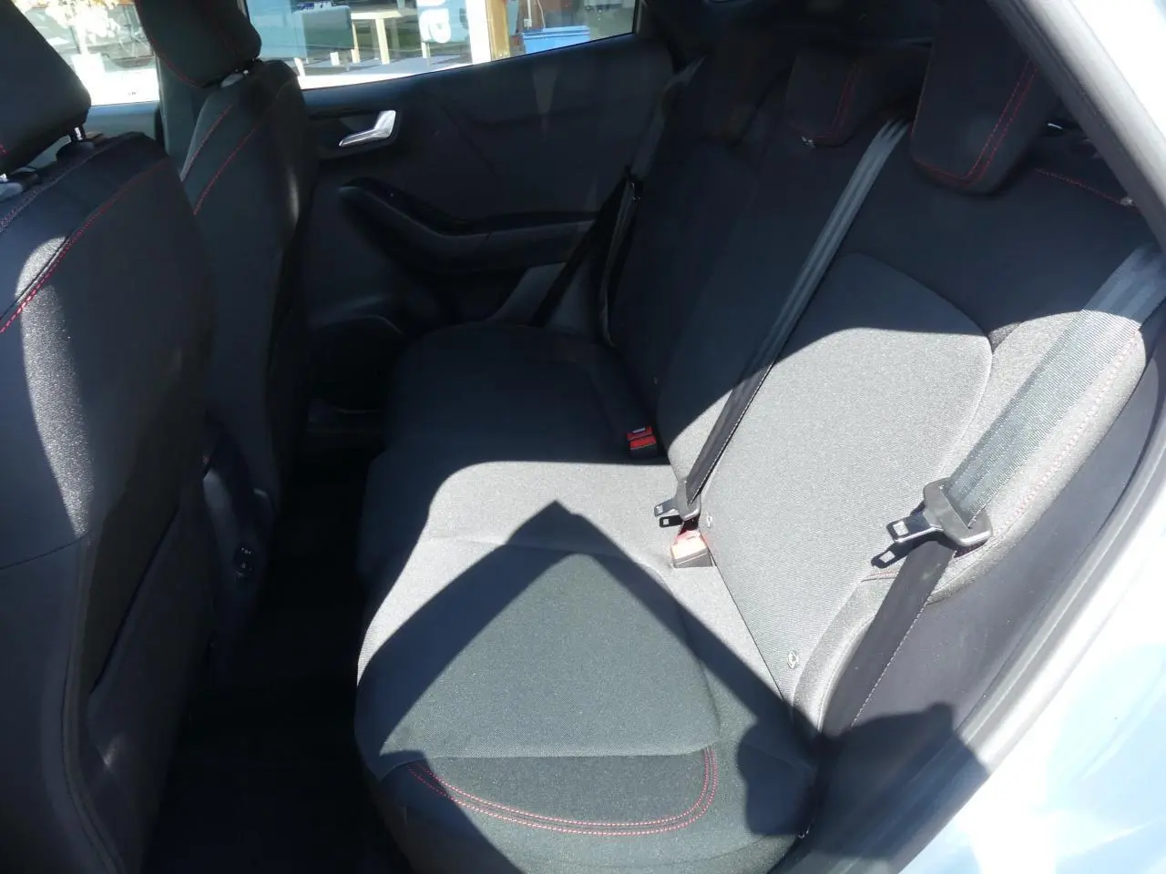 Vue latérale intérieure côté droit des sièges arrière noirs avec surpiqûres rouges du Ford Puma 2025 ST-Line.