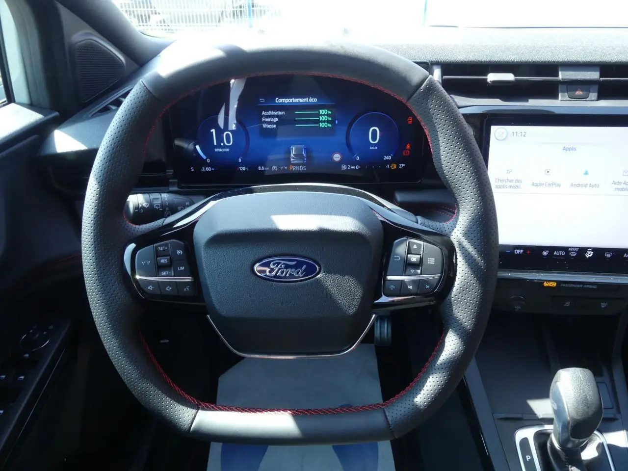 Vue intérieure centrée sur le volant perforé avec surpiqûres rouges et tableau de bord numérique du Ford Puma 2025.