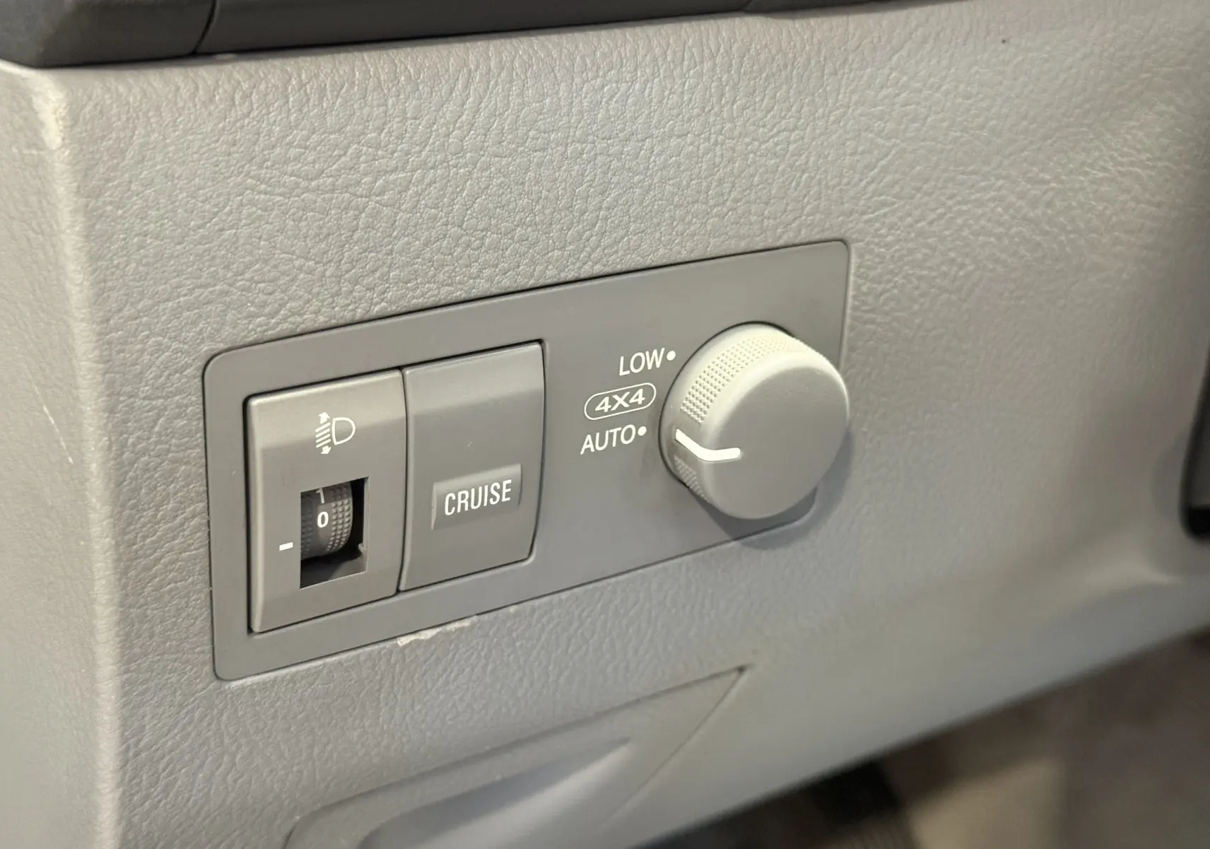 Gros plan sur les commandes 4x4 et régulateur de vitesse du tableau de bord gris du KIA Sorento 2005.