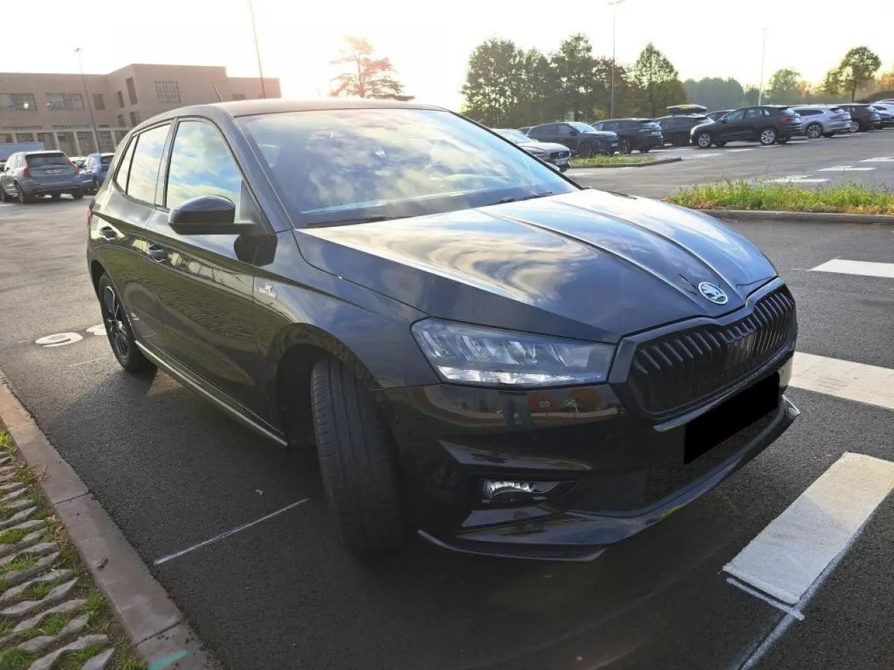 Vue 3/4 avant gauche d'une SKODA FABIA TSI 115 DSG Monte Carlo en Noir Magic avec calandre noire et phares LED allumés.