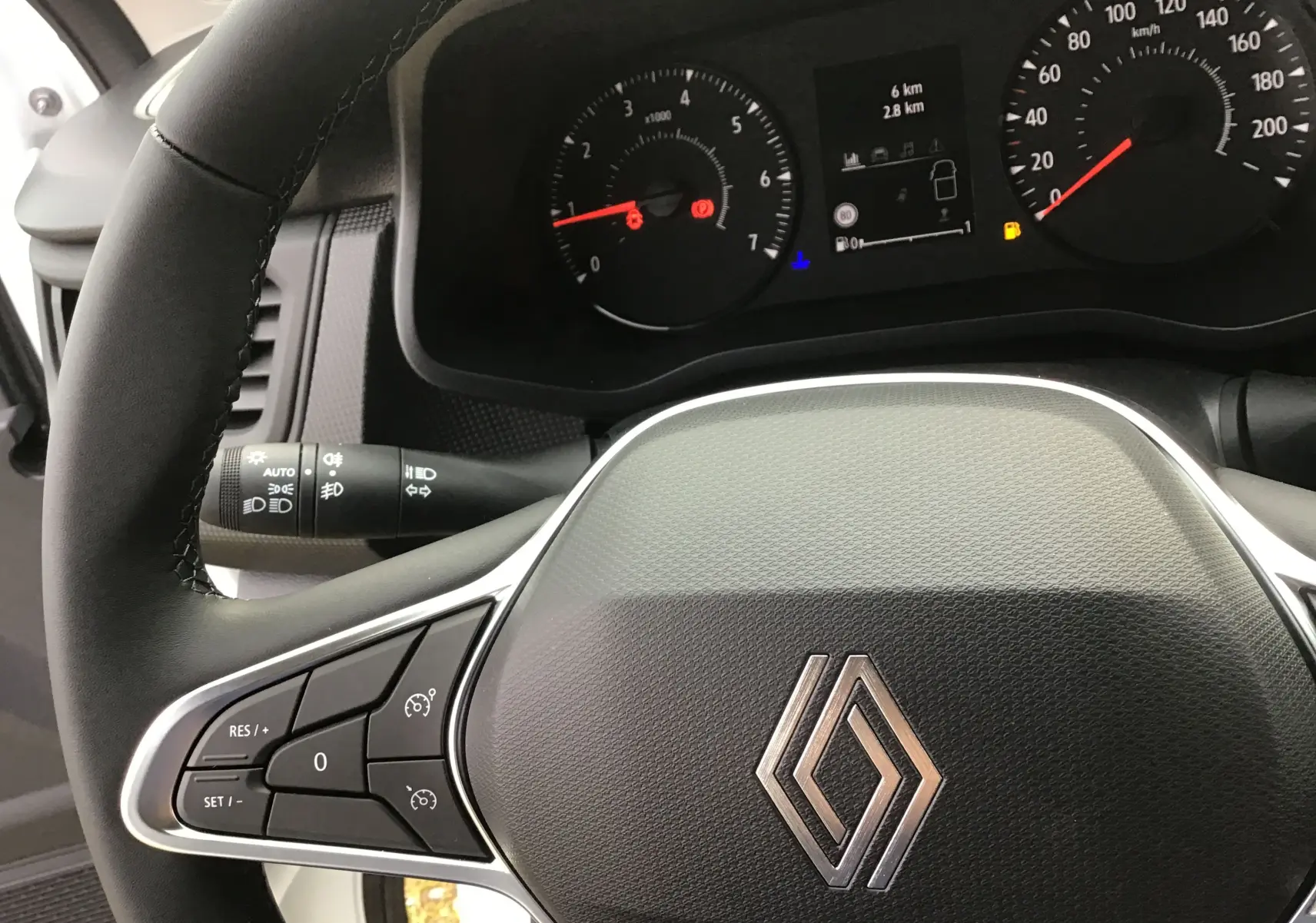 Vue rapprochée du volant et du tableau de bord du Renault Trafic Fourgon blanc, avec commandes au volant et affichage digital.