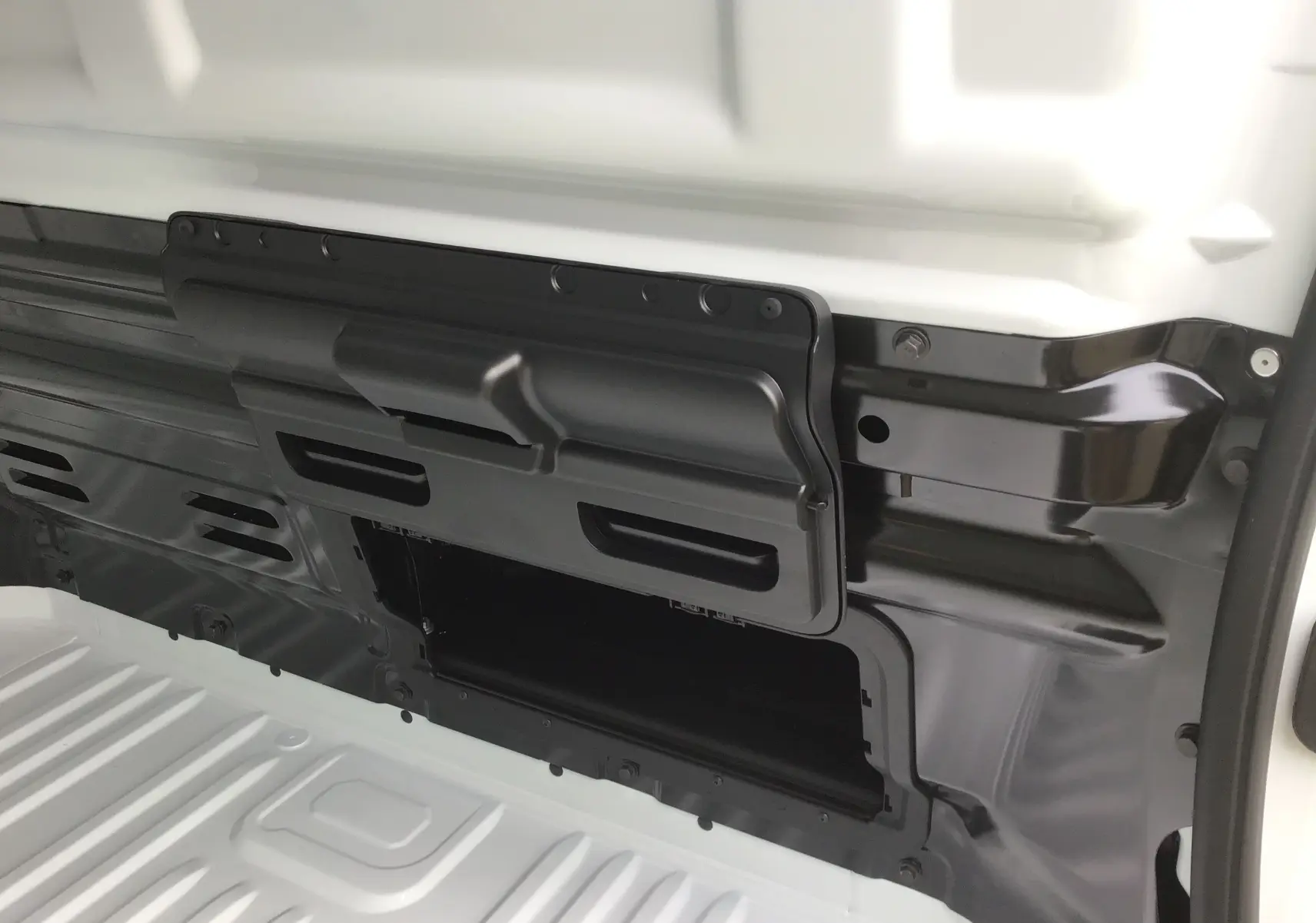Détail intérieur du compartiment de cloison noire dans le fourgon blanc Renault Trafic L1H1, vue rapprochée côté gauche.