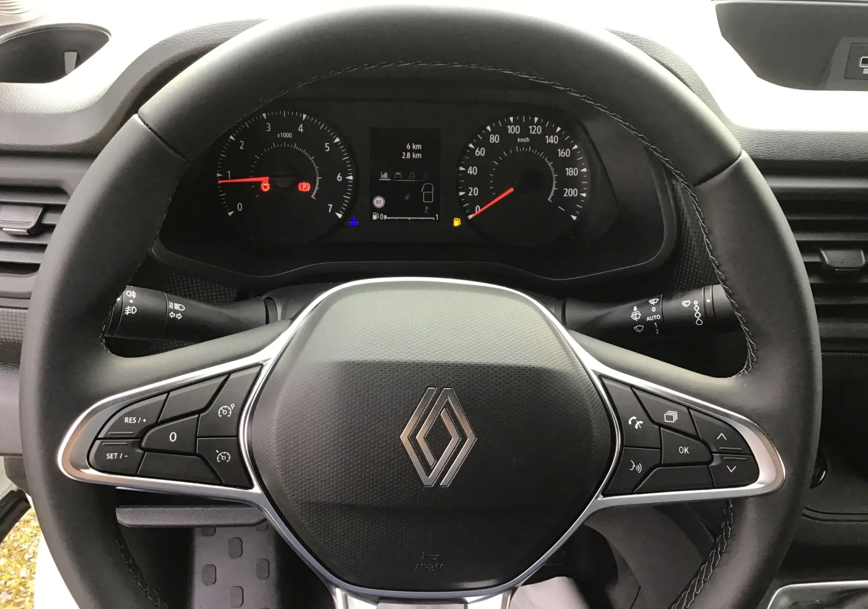 Vue rapprochée du volant noir du Renault Trafic Fourgon 2025 avec commandes intégrées et tableau de bord visible.