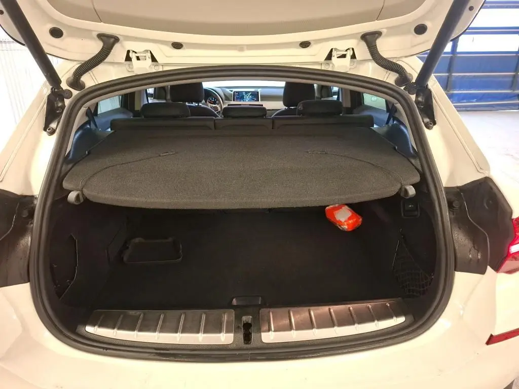 Coffre ouvert vu de l'arrière d'un BMW X2 blanc 2022, avec cache-bagages et intérieur noir visible.