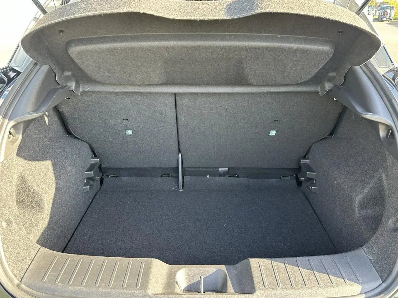 Coffre ouvert vu de l'arrière d'un Nissan Juke noir 2025, montrant l'espace de chargement vide et la garniture intérieure grise.