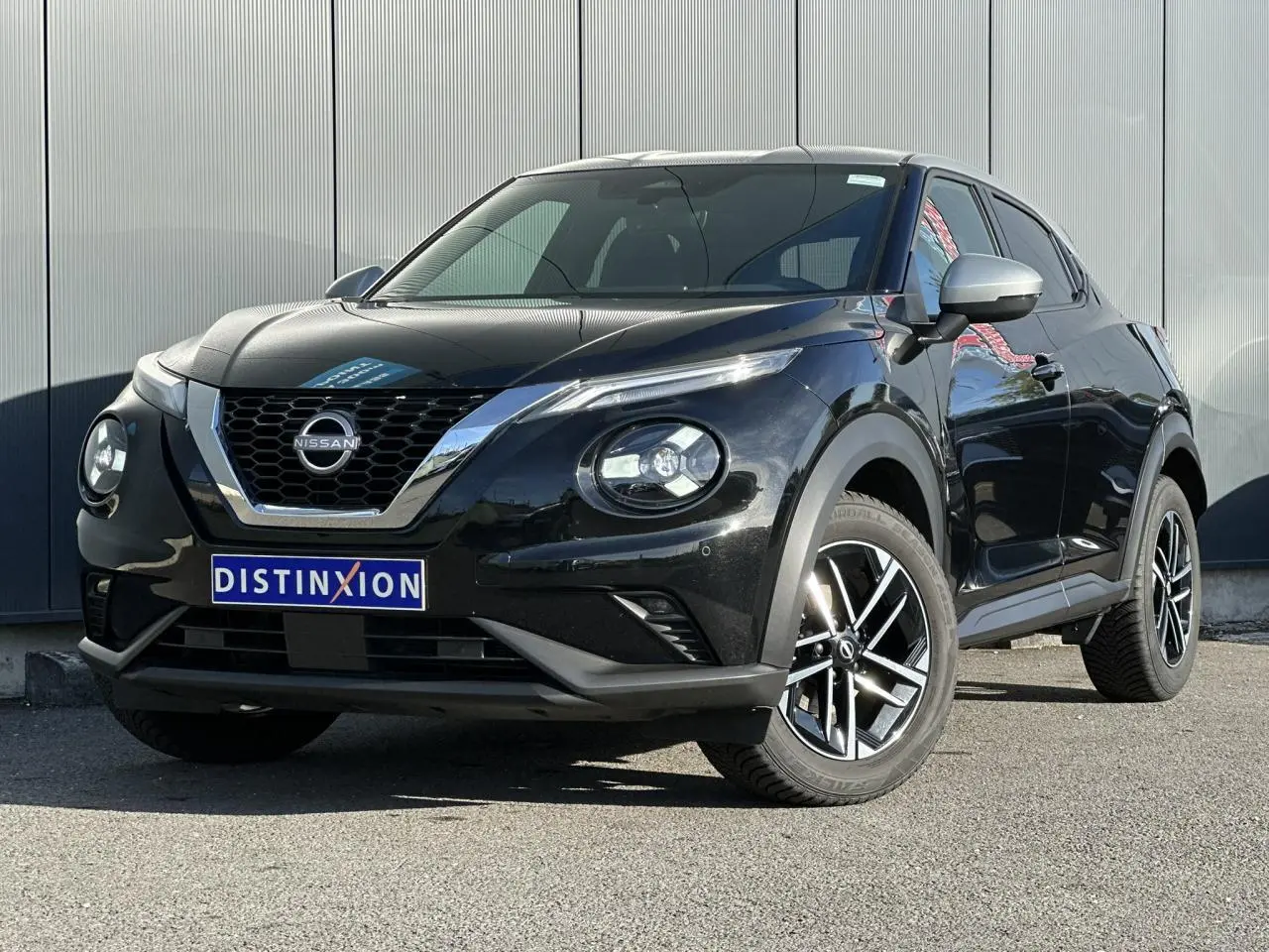 Nissan Juke noir en 3/4 avant droit, avec jantes alliage diamantées et calandre chromée brillante.